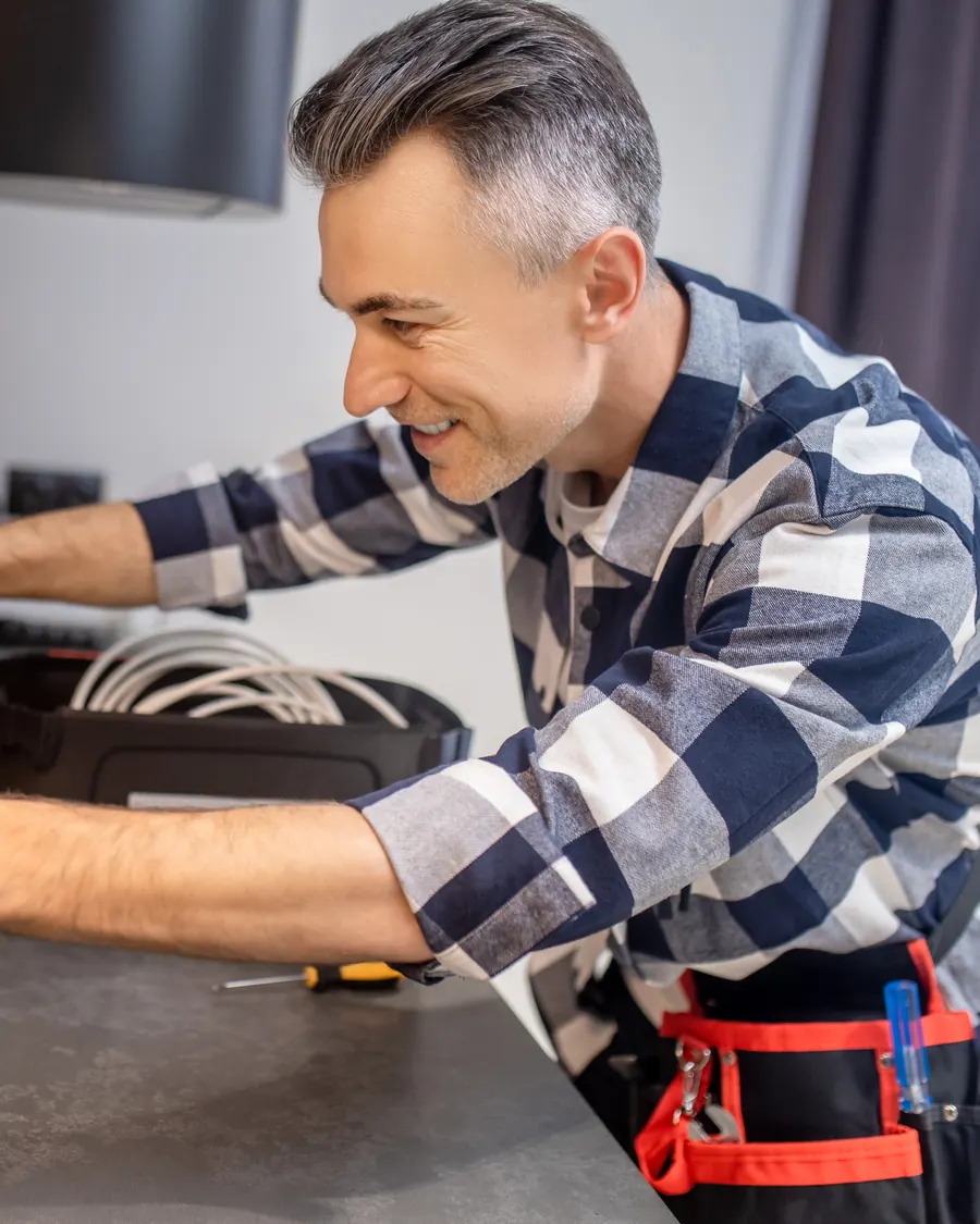 Un elettricista sorridente mette in bolla la scatola delle prese in una cucina