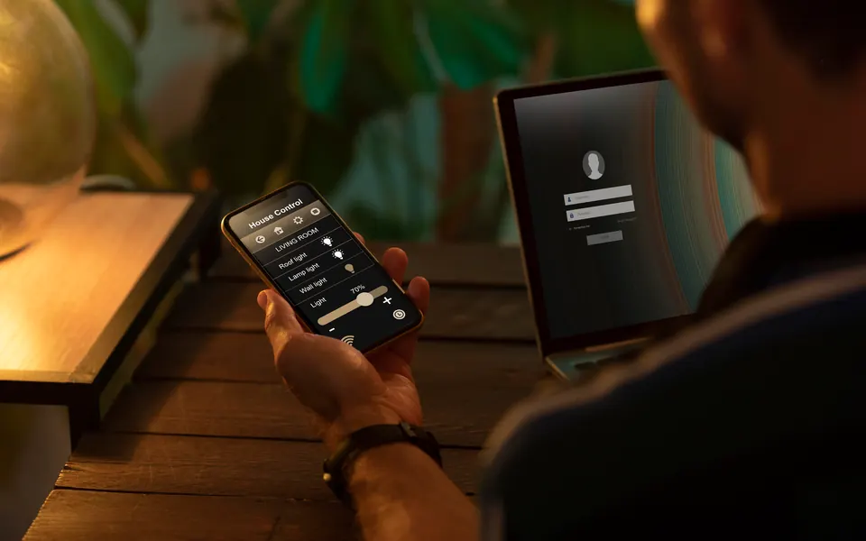 Una mano tiene il telefono con l'app che comanda le luci di casa
